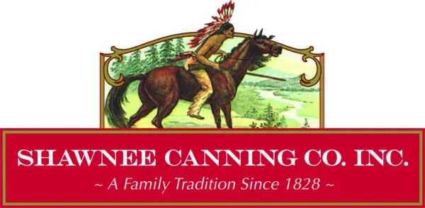 A person on horseback in traditional attire overlooks a scenic landscape. Text reads "SHAWNEE CANNING CO. INC." with "A Family Tradition Since 1828."