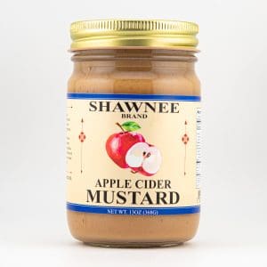 A jar of Shawnee brand apple cider mustard with a gold lid and label featuring an illustration of a sliced apple.
