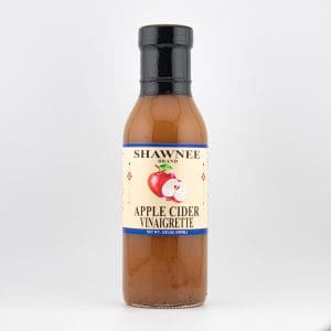 A bottle of Shawnee Brand Apple Cider Vinaigrette on a plain white background, featuring a label with red apples and decorative accents.
