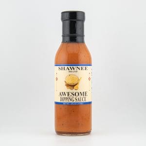 Bottle of Shawnee Brand Awesome Dipping Sauce, featuring an orange sauce with a label showcasing cheese and spoon image, set against a plain background.