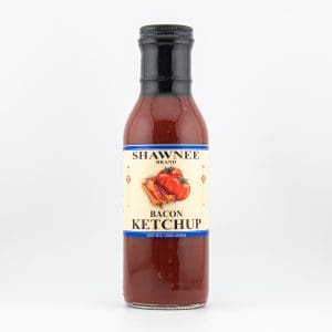 A bottle of Shawnee Brand Bacon Ketchup with a black cap, featuring a tomato and bacon illustration on the label against a plain background.
