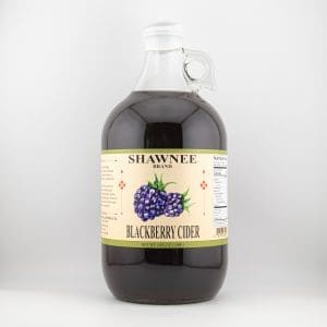 A large bottle of Shawnee Brand Blackberry Cider with a handle, featuring an illustrated blackberry label and nutrition information, set against a plain background.