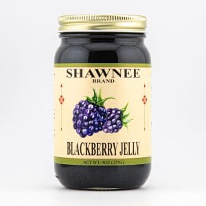 A jar labeled "Shawnee Brand Blackberry Jelly" with a gold lid and an illustrated blackberry design on the front, set against a plain background.