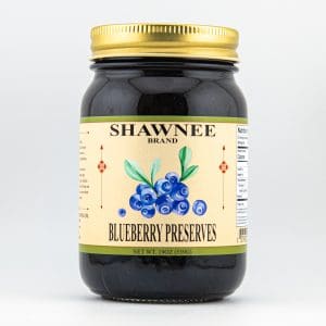 A jar of Shawnee Brand Blueberry Preserves, featuring a decorative label with blueberries, a gold lid, and nutrition information on the side.