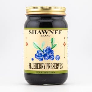 A jar labeled "Shawnee Brand Blueberry Preserves" with blueberries and leaves on the label, against a plain white background.