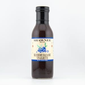 A bottle of Shawnee Brand Blueberry Balsamic Vinaigrette, featuring a blue label with blueberry illustration, set against a plain white background.