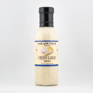 A bottle of Shawnee Brand Cheesy Garlic Dressing with garlic and cheese images on the label, set against a plain white background.