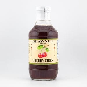 A bottle of Shawnee Brand Cherry Cider with a light yellow label featuring red cherries and product details against a plain background.