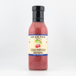 A bottle of Shawnee Brand Cherry Poppyseed Dressing, featuring a cherry illustration on the label, stands against a plain white background.