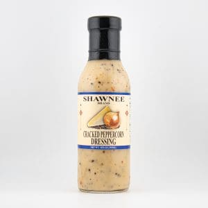 A bottle of Shawnee Brand Cracked Peppercorn Dressing with black top, featuring an image of peppercorns on the label, against white background.