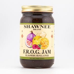 A jar of Shawnee Brand F.R.O.G. Jam, featuring fig, raspberry, orange, and ginger, with colorful fruit illustrations on the label.