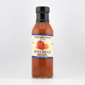 A bottle of Shawnee brand Honey French Dressing with a label featuring tomatoes and honeycomb. White background highlights the product's vibrant color.