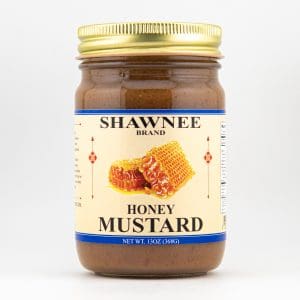 A jar of Shawnee Brand Honey Mustard with a gold lid, featuring honeycomb images on the label against a plain white background.
