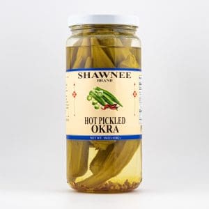 A jar labeled "Shawnee Brand Hot Pickled Okra" contains pickled okra spears in brine, photographed against a plain background.
