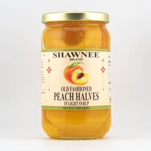 A jar of Shawnee brand old fashioned peach halves in light syrup, featuring a peach illustration on the label, against a plain background.