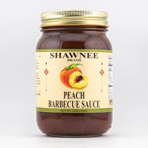 A jar of Shawnee brand peach barbecue sauce with a label featuring peaches, displayed against a plain white background.