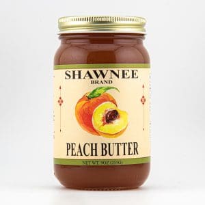 A jar of Shawnee Brand Peach Butter, featuring a colorful peach illustration on the label, with a gold lid. Net weight: 9 oz.