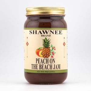 A jar of Shawnee Brand's "Peach on the Beach Jam" with colorful fruit illustration and a gold lid. Net weight: 9 oz (255g).