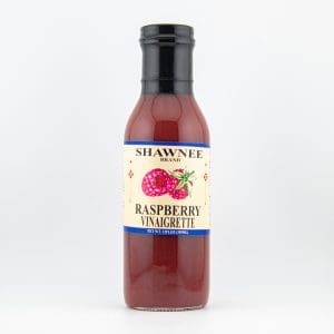 A bottle of Shawnee Brand Raspberry Vinaigrette showcasing a vibrant label featuring raspberries on a plain, light background.