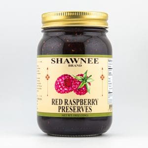 A jar of Shawnee Brand red raspberry preserves with a golden lid, featuring a label showing raspberries, on a plain white background.