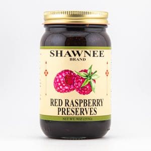 A jar of Shawnee Brand red raspberry preserves featuring a label with illustrated raspberries, gold lid, and capacity of 9 ounces (255 grams).