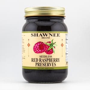 A jar of Shawnee brand seedless red raspberry preserves with a gold lid, featuring a red raspberry label design against a white background.