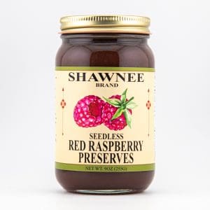 A jar of Shawnee Brand seedless red raspberry preserves, displaying vibrant raspberry illustrations on the label against a white background.