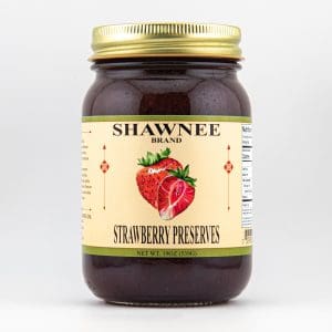 A jar of Shawnee Brand strawberry preserves with a gold lid, featuring a strawberry illustration on the label, against a plain background.