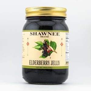 A jar of Shawnee Brand elderberry jelly with a gold lid, featuring a label illustration of elderberry leaves and berries.