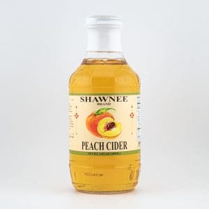 A bottle of Shawnee Brand Peach Cider with a light peach-colored liquid, featuring a label with a peach illustration against a plain background.