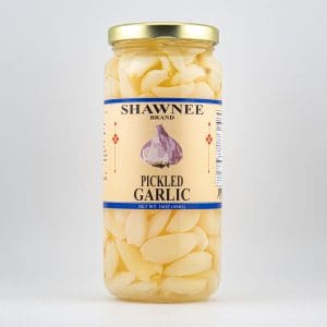 A jar of Shawnee Brand pickled garlic, featuring peeled cloves in brine. The label shows a garlic illustration and product details.