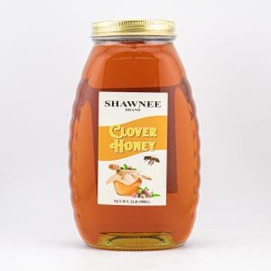 A jar of Shawnee Brand Clover Honey with a golden lid, adorned with a label featuring honey dipper and bee illustrations.