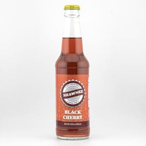 A glass bottle of Shawnee Black Cherry soda with a red label and yellow cap, against a plain white background.