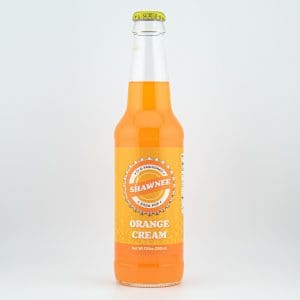 A bottle of Shawnee soda pop, featuring Orange Cream flavor, with a simple label design on a plain light background.