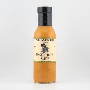 A bottle of Shawnee Brand Finger Lickin' Sauce with a beige label and black cap, featuring an illustrated character on the front.