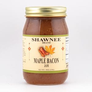 A jar of Shawnee Brand Maple Bacon Jam, featuring a gold lid and label with a maple leaf and bacon illustration.