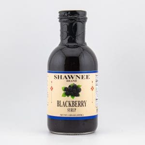 A bottle of Shawnee brand blackberry syrup, featuring a label with fruit illustrations and details. The container is small, with a dark liquid.