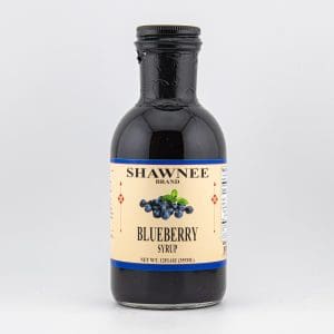 A bottle of Shawnee Brand Blueberry Syrup is displayed, featuring a label with blueberry images, set against a neutral background.