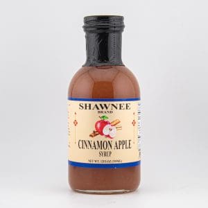 A bottle of Shawnee Brand Cinnamon Apple Syrup with a beige label, featuring apple and cinnamon images against a plain gray background.