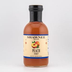 A 12 fl oz bottle of Shawnee Brand Peach Syrup with a yellow label featuring a peach illustration against a plain background.