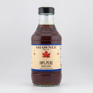 A clear bottle labeled "Shawnee Brand 100% Pure Maple Syrup" with a red maple leaf design, containing dark syrup, sits against a neutral background.