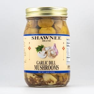 A jar of Shawnee Brand Garlic Dill Mushrooms, showcasing mushrooms and garlic cloves. The label provides product details, with a volume of 16oz (454g).
