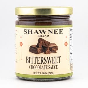 Jar of Shawnee Brand bittersweet chocolate sauce with golden lid, featuring an image of chocolate chunks on a cream-colored label. Net weight: 10 oz.
