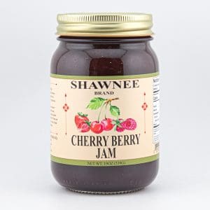 A jar of Shawnee Brand Cherry Berry Jam, featuring a label with illustrations of cherries, strawberries, and raspberries, against a plain background.