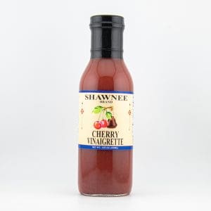 A bottle of Shawnee Brand Cherry Vinaigrette with a black cap and a creamy label featuring cherries and brand details on a white background.