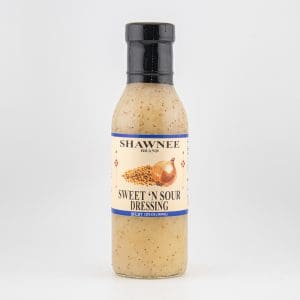 A bottle of Shawnee Brand Sweet 'N Sour Dressing is displayed against a plain, white background. The label features onions and seeds.